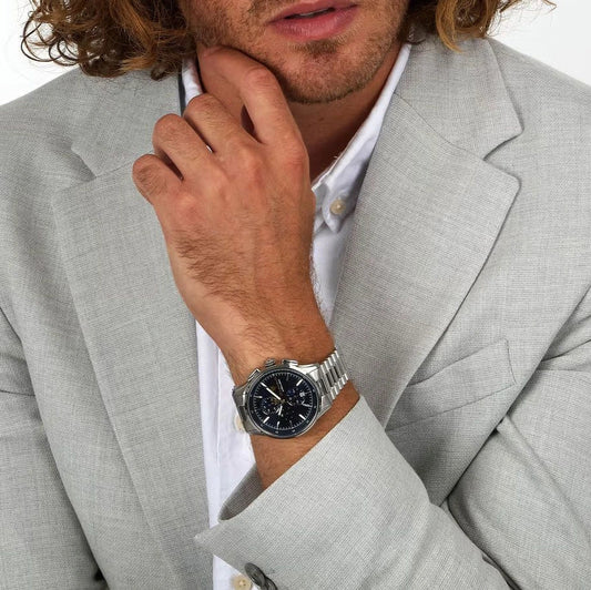 Man wearing a gray suit and silver watch with a white background
